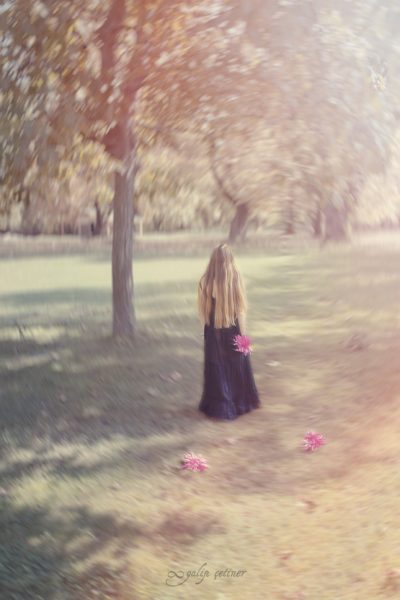 the girl with a black dress is leaving between the trees