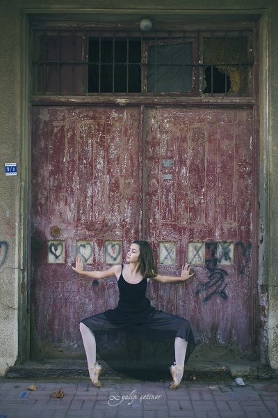 black dressed ballerina girl is on her pointes in front of the old door