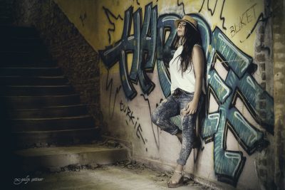 the portrait of the rebel girl standing in front of the graffiti wall